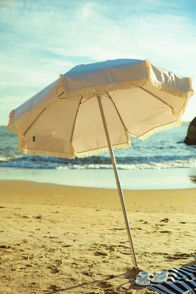 Guarda-sol Rive com franjas em uma praia